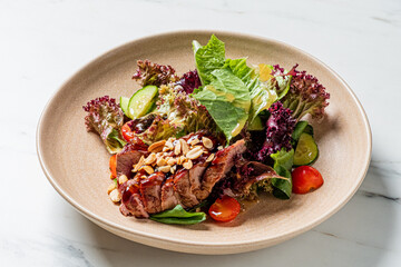 Delicious dish features duck breast slices with fresh vegetables and nutty garnish