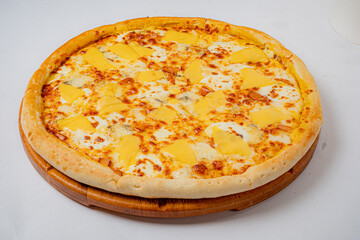 A quattro formaggi pizza is displayed. It contains yellow cheeses and sits on a wooden tray