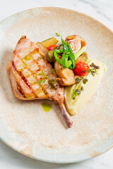 A chop meal. It is a delicious dinner. Vegetables complete the dish on a fancy plate