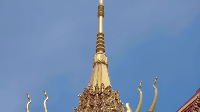 Majestic tiled Buddhist temple roof with golden intricate gable and serpent-like chofas. Shot in motion