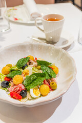A Nicoise salad and a cup of tea are presented on a white table