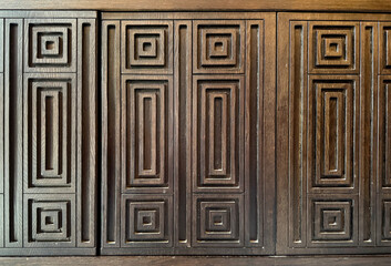 Detail of geometric rectangular pattern carving on a dark wood surface. Antique retro concept. For carpentry, doors, and wall panel. Modern vintage classic feel. Seamless background texture.