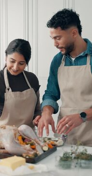 Food, couple and cooking turkey in kitchen, vegetable stuffing and thanksgiving dinner in home. Happy man, woman and meal prep for holiday with meat, talk or help with ingredients for festive recipe