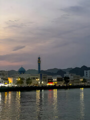  Mosque reflecting on calm waters at sunset in Muscat.Scenic reflection of a mosque in the calm waters of Muscat, Oman during golden hour.

