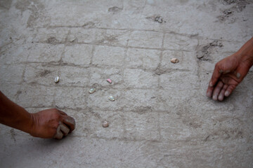 Village women playing with seashells on muddy ground, traditional rural game from South Asia