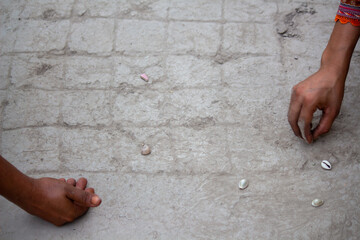 Village women playing with seashells on muddy ground, traditional rural game from South Asia