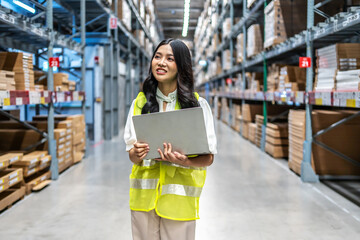 Focused on her task, Young asian woman holding laptop computer meticulously updates inventory...