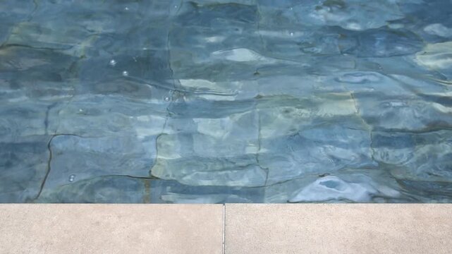 swimming pool tile edge with clear water and gentle water ripples surface