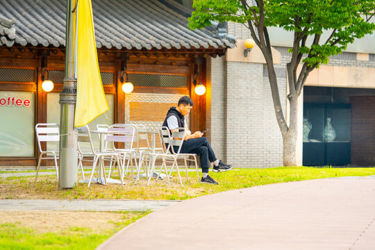 Asian man sitting on steel chair and watching smartphone in the park. Chilling