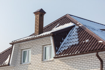 A house with a chimney and a roof covered in snow
