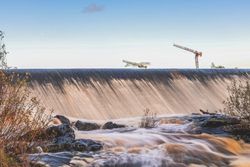 Artificial fish ladder in a river with water flowing over concrete steps, designed to help wild salmon migrate upstream through the dam, symbol of ecological restoration