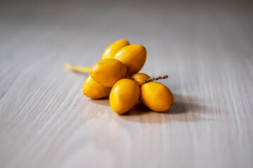 yellow plums on wooden table, bunch of ripe date palm fruits (phoenix dactylifera) isolated on white table close up