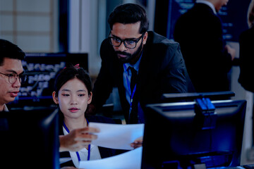 Critical AI model review. Senior data scientist leans over analyzing code output with junior engineers. Debugging complex algorithms together for optimal service performance at night.