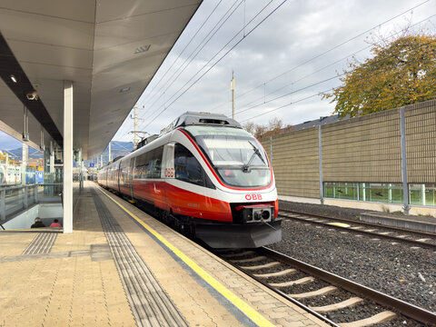 Villach, Austria - October 23, 2025: OEB train arriving at modern railway station platform with sleek design and autumn foliage in the background, showcasing public transportation in urban setting