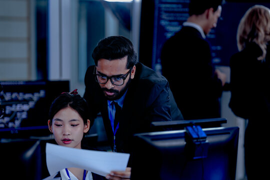 Critical AI model review. Senior data scientist leans over analyzing code output with junior engineers. Debugging complex algorithms together for optimal service performance at night.