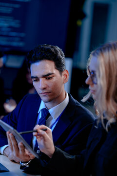 A data analyst scrolls through complex visualizations on a tablet comparing results against code displayed onscreen working late to finalize a critical business intelligence report.