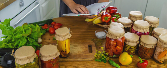 Woman canning vegetables in jars in the kitchen. Selective focus.