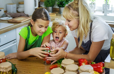 Family canning vegetables in jars in the kitchen. Selective focus.