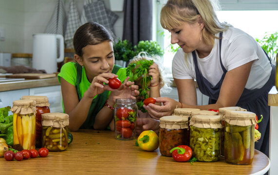 Family canning vegetables in jars in the kitchen. Selective focus.