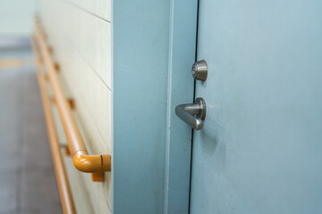 Close-up at handle of service room's metal door that closed. Selective focus at door handle part.