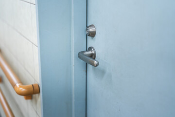 Close-up at handle of service room's metal door that closed. Selective focus at door handle part.