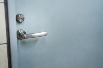 Close-up at handle of service room's metal door that closed. Selective focus at door handle part.