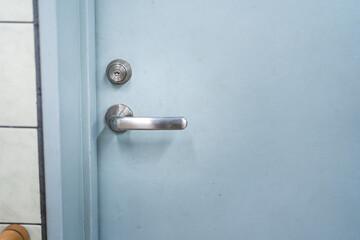 Close-up at handle of service room's metal door that closed. Selective focus at door handle part.