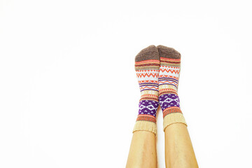 Warm patterned socks on relaxed feet over white background. Symbol of domestic tranquility and slow mornings. Relates to sustainable fashion, ethical design, and seasonal warmth during cold months.