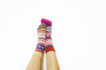 Legs displaying mismatched Fair Isle socks against minimalist backdrop. Concept of warm moments, winter cozy, comfort lifestyle choice, authenticity, trends in natural living, and sustainable fashion.