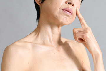 肌を気にする困り顔の中高年のアジア人女性