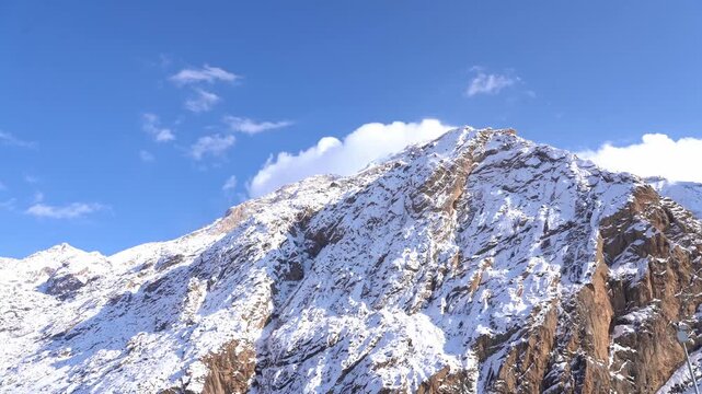 Cinematic view of snowy Mount Sumbul in Hakkari at sunset, majestic snow-capped mountain peaks under blue sky with clouds, winter landscape in Eastern Turkey, 4K 25fps. 8