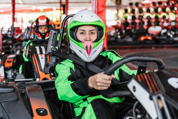 Young woman in racing suit and helmet preparing to drive a kart, focusing on the track ahead at a karting circuit