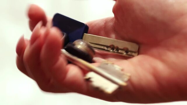 Female hand fidgeting with house keys in her palm, close-up.