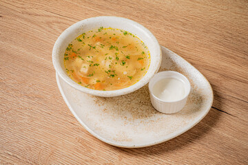 A bowl of delicious chicken soup with veggies sits next to creamy dip, brightening the table