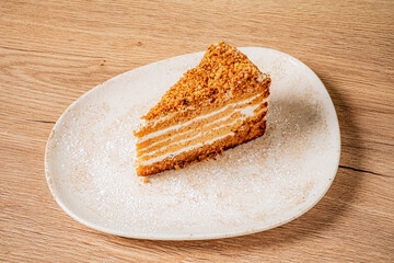 A fluffy slice of layer cake on a rustic plate awaits a warm drink