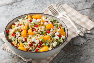 delicious, vitamin-rich quinoa salad with spinach, feta, tangerines, pomegranate, and pistachios, close-up in a bowl on the table. Horizontal