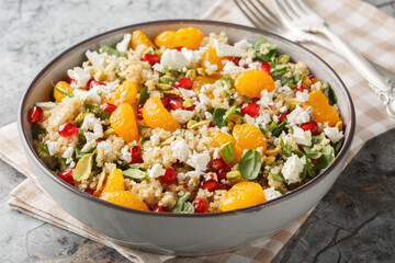 Pomegranate and Orange Quinoa Salad with added spinach,  feta and crispy pistachios closeup on the plate on the table. Horizontal