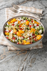 Winter Pomegranate Orange Quinoa Salad with spinach, feta, and pistachios closeup on the plate on the table. Vertical