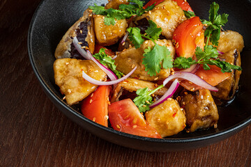 Colorful mix of tofu, tomatoes, and herbs garnished with sesame seeds on a wooden surface