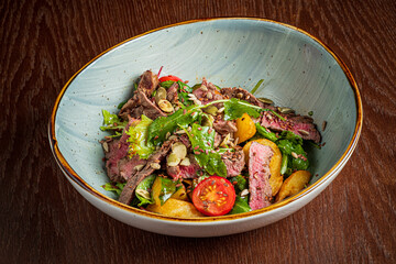 A delightful bowl of beef salad filled with fresh greens, ripe tomatoes, and crunchy toppings