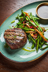 A perfectly cooked steak and sautéed green beans create a delicious meal on a vibrant plate