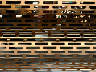 Close up of gold metallic perforated metal plate. Suitable for divider, screens, or roller shutter. Luxurious contemporary modern industrial feel. Seamless background texture