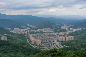Panoramic View of Residential City Development in Lush Green Mountain Valley Under Cloudy Sky, view from the top of the mountain