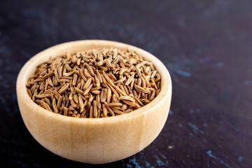 caraway in a wooden bowl on a dark background