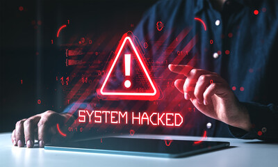 Cybersecurity warning with red alert triangle and system hacked message on digital screen in front of user touching tablet interface in dark room.