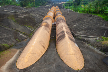 Giant penstock pipes at the Saguling Hydroelectric Power Plant in West Java, Indonesia. These massive pipes channel water to turbines, generating renewable energy.