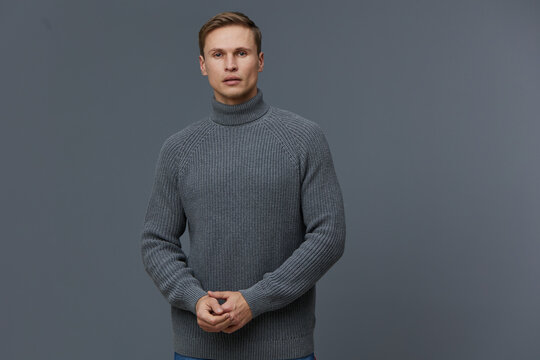 Young caucasian man wearing grey knitted sweater standing isolated on dark grey background looking at camera digital nomad concept