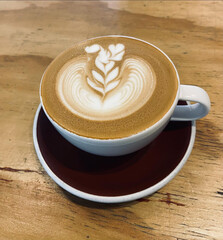 Latte art coffee served on wooden table.