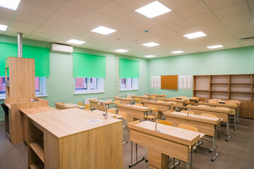 A modern classroom in a school or educational institution. A blackboard with several chalk writing panels and an interactive digital panel.