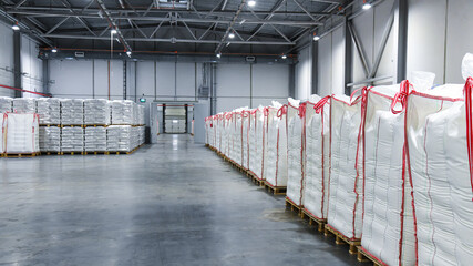 Large stacks of white bags, neatly stacked on wooden pallets and wrapped in transparent plastic.